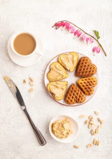 Homemade waffle with peanut butter and cup of coffee on a gray concrete background. top view, flat