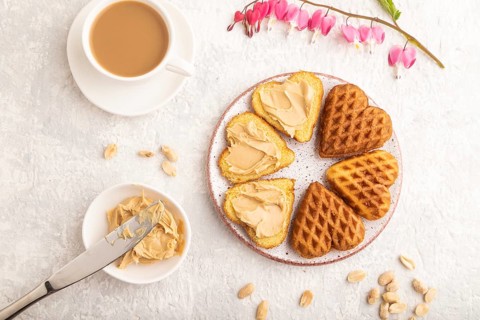 Homemade waffle with peanut butter and cup of coffee on a gray concrete background. top view, flat