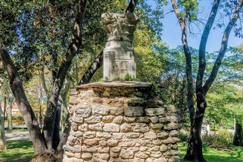 Base and capstone of roman column on top of section of stone wall in park in Istanbul, Tuerkiye
