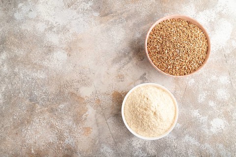 Powdered milk and buckwheat baby food mix, infant formula on brown concrete background. Top view,