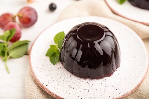 Black currant and grapes jelly on white wooden background and linen textile. side view, close up,