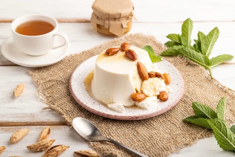 Ricotta cheese with honey and almonds on white wooden background and linen textile. side view,