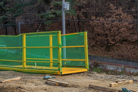 Yellow crane lifting platform at mountainside construction site