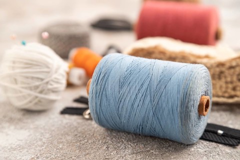 Sewing accessories: scissors, thread, thimbles, braid on brown concrete background. Side view,