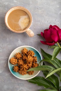 Homemade soft caramel fudge candies on blue plate and cup of coffee on gray concrete background,