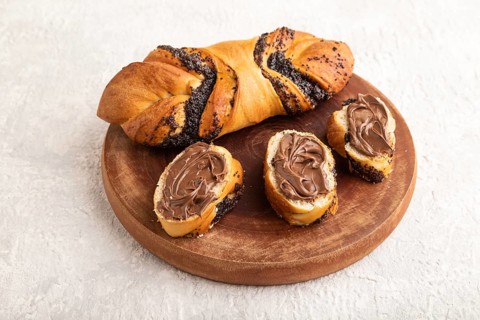 Homemade sweet bun with chocolate cream on a gray concrete background. side view, close up