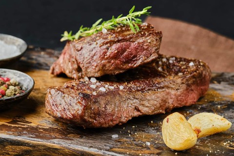 Closeup view of uncut beef strip steak on cutting board