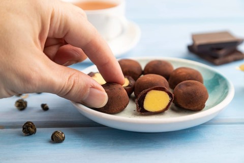 Japanese rice sweet buns chocolate mochi filled with cream and cup of green tea with hand on blue