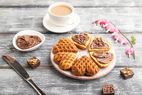 Homemade waffle with chocolate butter and cup of coffee on a gray wooden background. side view,