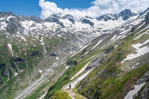 Mountaineer on hiking trail in picturesque mountain landscape, in the background mountain peak