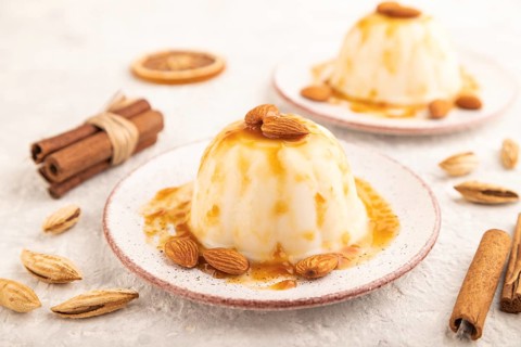 White milk jelly with caramel sauce on gray concrete background. side view, close up, selective
