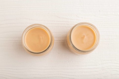Baby puree with fruits mix, apple, banana infant formula in glass jar on white wooden background.