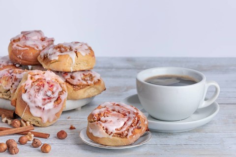 Homemade cinnamon buns next to cup with coffee, copy space, white background