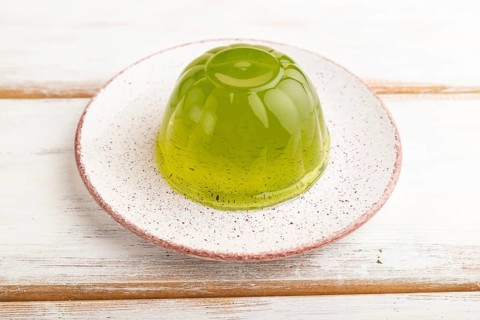 Mint green jelly on white wooden background. side view, close up
