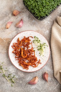 Fried Cordyceps militaris mushrooms on brown concrete background with microgreen, herbs and spices.