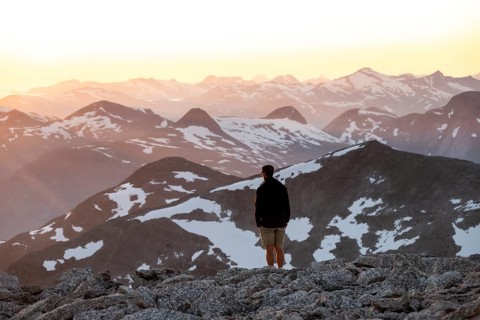 Mountaineer enjoying the view, mountain panorama at the summit of Skala at sunset, Loen, Norway,