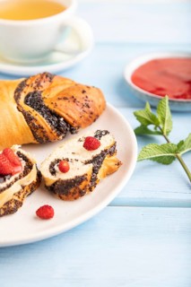 Homemade sweet bun with strawberry jam and cup of green tea on a blue wooden background. side view,