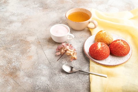 Traditional french custard dessert shu cake and cup of green tea on brown concrete background and