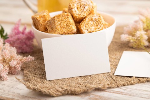 White business card with traditional turkish delight (rahat lokum) in white ceramic bowl on a white