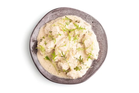 Stewed chicken fillets with coconut milk sauce and mizuna cabbage microgreen isolated on white