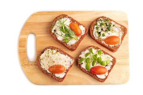 Red beet bread sandwiches with cream cheese, tomatoes and microgreen isolated on white background.