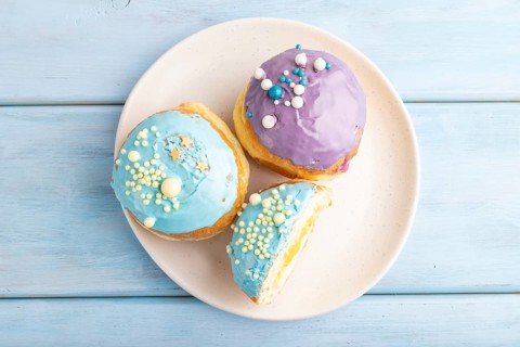 Purple and blue glazed donut on blue wooden background. top view, flat lay. Breakfast, morning,