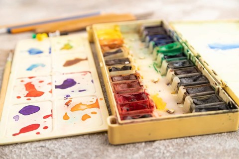 Drawing accessories set: brushes, pencils, watercolor on brown concrete background. Side view,