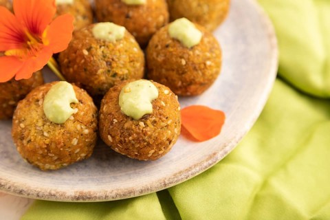 Falafel with guacamole on white concrete background and green linen textile. Side view, close up,
