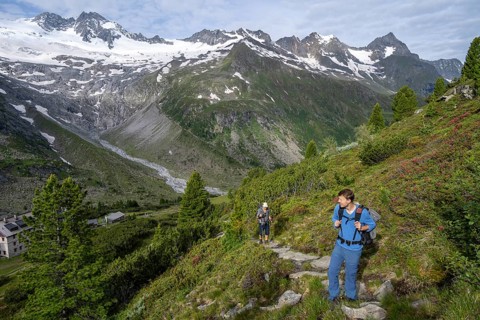 Two mountaineers on a hiking trail in a picturesque mountain landscape with alpine roses, in the