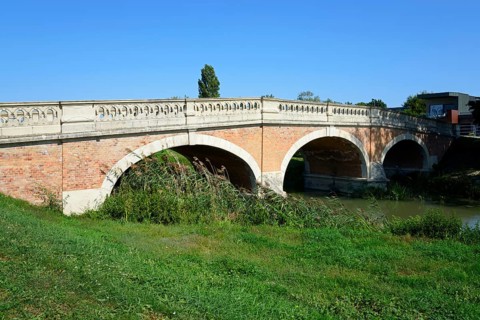 A brick arch bridge over a small river in the countryside under a clear blue sky, Baroque Art