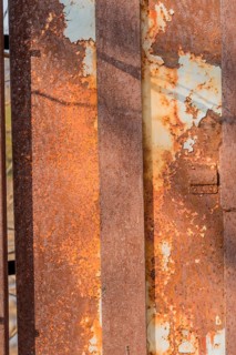 Side view of old electrical switch box inside rusty metal utility box security cage