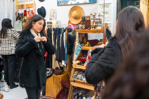 Young and beauty woman trying on a jacket in a clothing store during sales