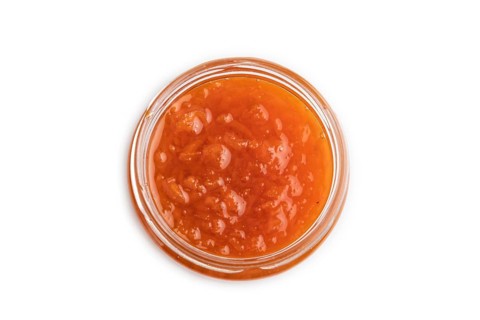 Carrot jam with cinnamon in glass jar isolated on white background. Top view, flat lay, close up