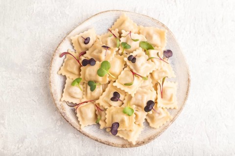 Dumplings with pepper, salt, herbs, microgreen on gray concrete background. Top view, flat lay,