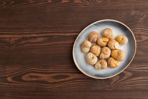 Grape (Burgundy) snails with butter and cheese on brown wooden background. Top view, flat lay, copy
