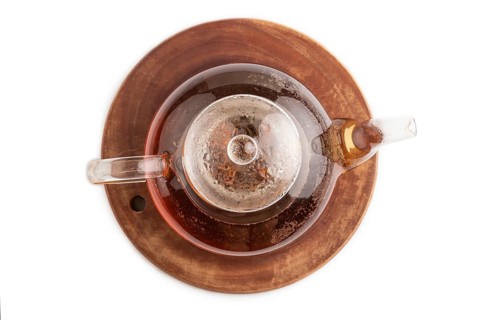Red tea with herbs in glass teapot isolated on white background. Healthy drink concept. Top view,