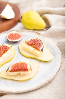 Summer appetizer with pear, cottage cheese, figs and honey on a white wooden background and linen