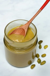 Pistachio cream in jar with spoon, pistachios