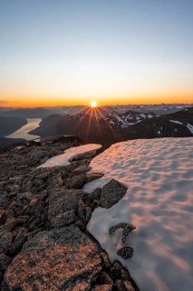 View of mountains and fjord Faleidfjorden, sun star at sunset, summit of Skala, Loen, Norway,