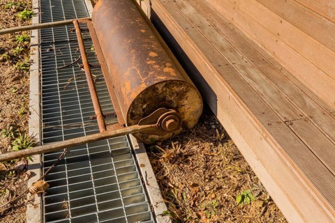 Hand pushed surface roller in front of wooden stadium benches at edge of dirt field