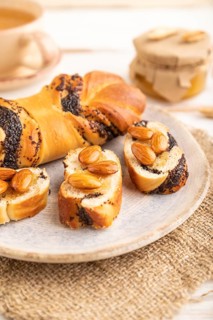 Homemade sweet bun with honey almonds and cup of green tea on a white wooden background and linen