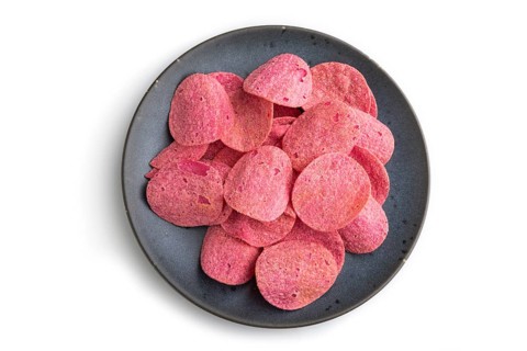 Red potato chips with herbs and tomatoes on blue cearmic plate isolated on white background. Top