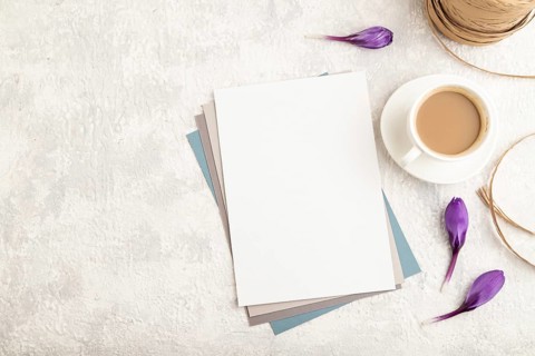 White paper sheet mockup with spring snowdrop crocus flowers and cup of coffee on gray concrete