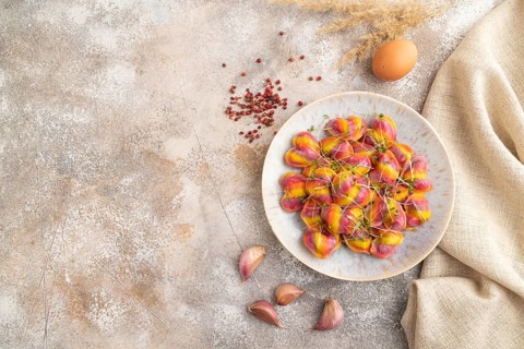 Rainbow colored dumplings with pepper, herbs, microgreen on brown concrete background and linen