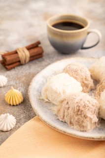 Traditional arabic sweets pishmanie and a cup of coffee on brown concrete background and orange