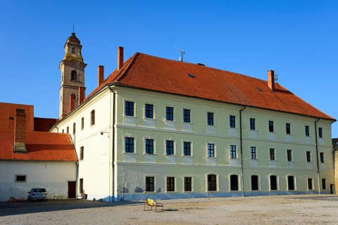 Historic building under a blue sky with a prominent tower in the midst of peaceful surroundings,