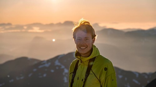 Mountaineer on the summit of Skala with cairn, view of mountain landscape and fjord Faleidfjorden,