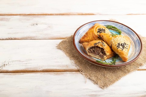 Homemade asian pastry samosa on white wooden background and linen textile. side view, copy space