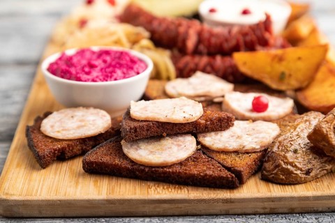 Set of snacks: sausages, toast, sauerkraut, marinated onion and cucumber, baked potato on a cutting