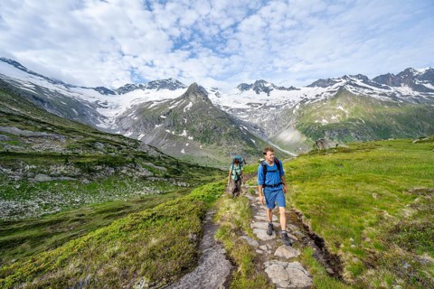 Two mountaineers on a hiking trail in a picturesque mountain landscape, mountain peaks with snow